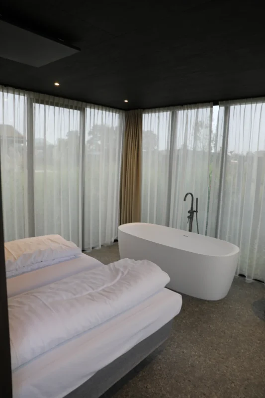 Vrijstaand bad naast een bed in een lodge op Soof aan de Rijn