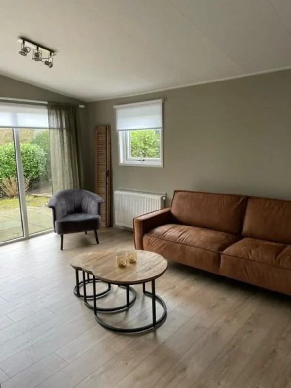 Woonkamer met bank en glazen deuren in het Boshuis op Familiehuis Nunspeet