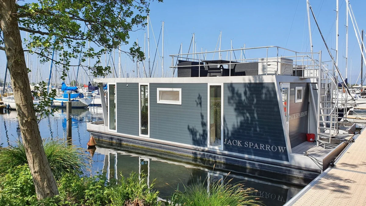 Havenlodge met dakterras afgemeerd tussen de zeilboten bij Marina Muiderzand